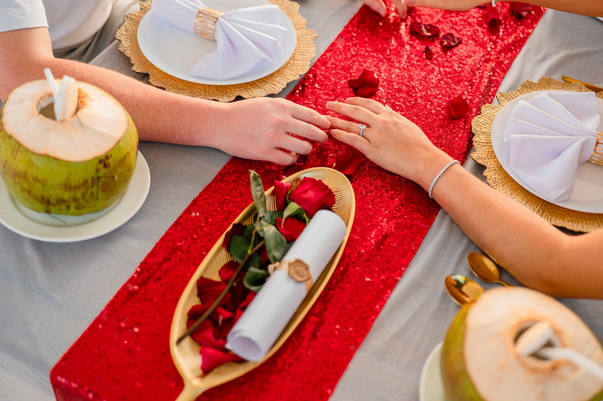 Romantic dinner for two with red table décor, tropical coconuts and elegant place settings after a proposal in Pattaya.
