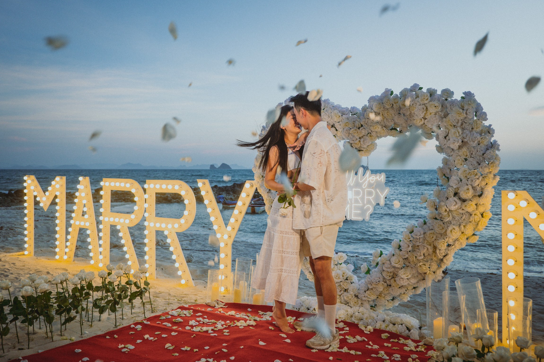 Romantic beach proposal setup in Koh Samui, Thailand with candles, flowers and ocean sunset view.