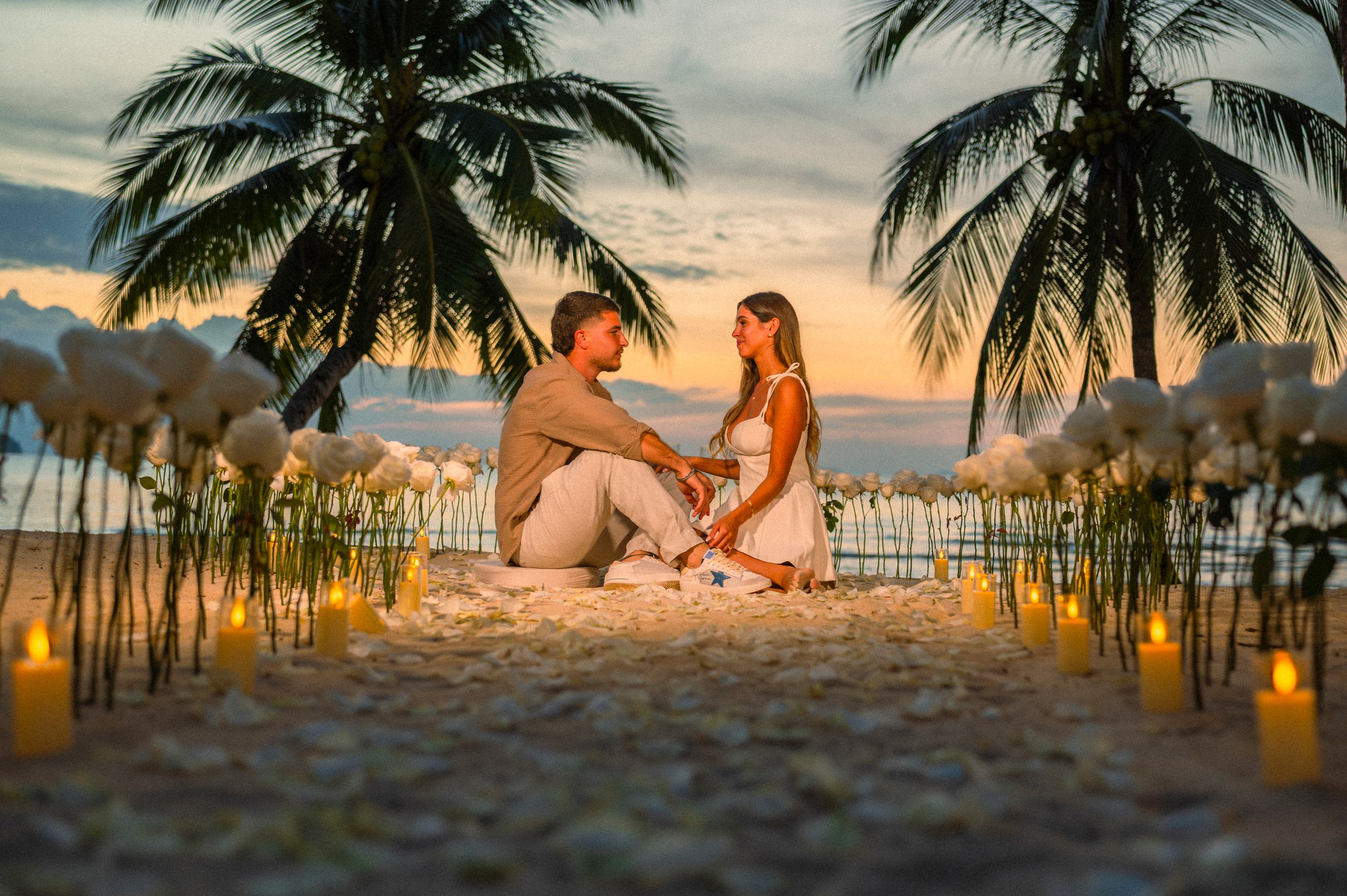 Romantic beach proposal setup in Koh Samui, Thailand with candles, flowers and ocean sunset view.