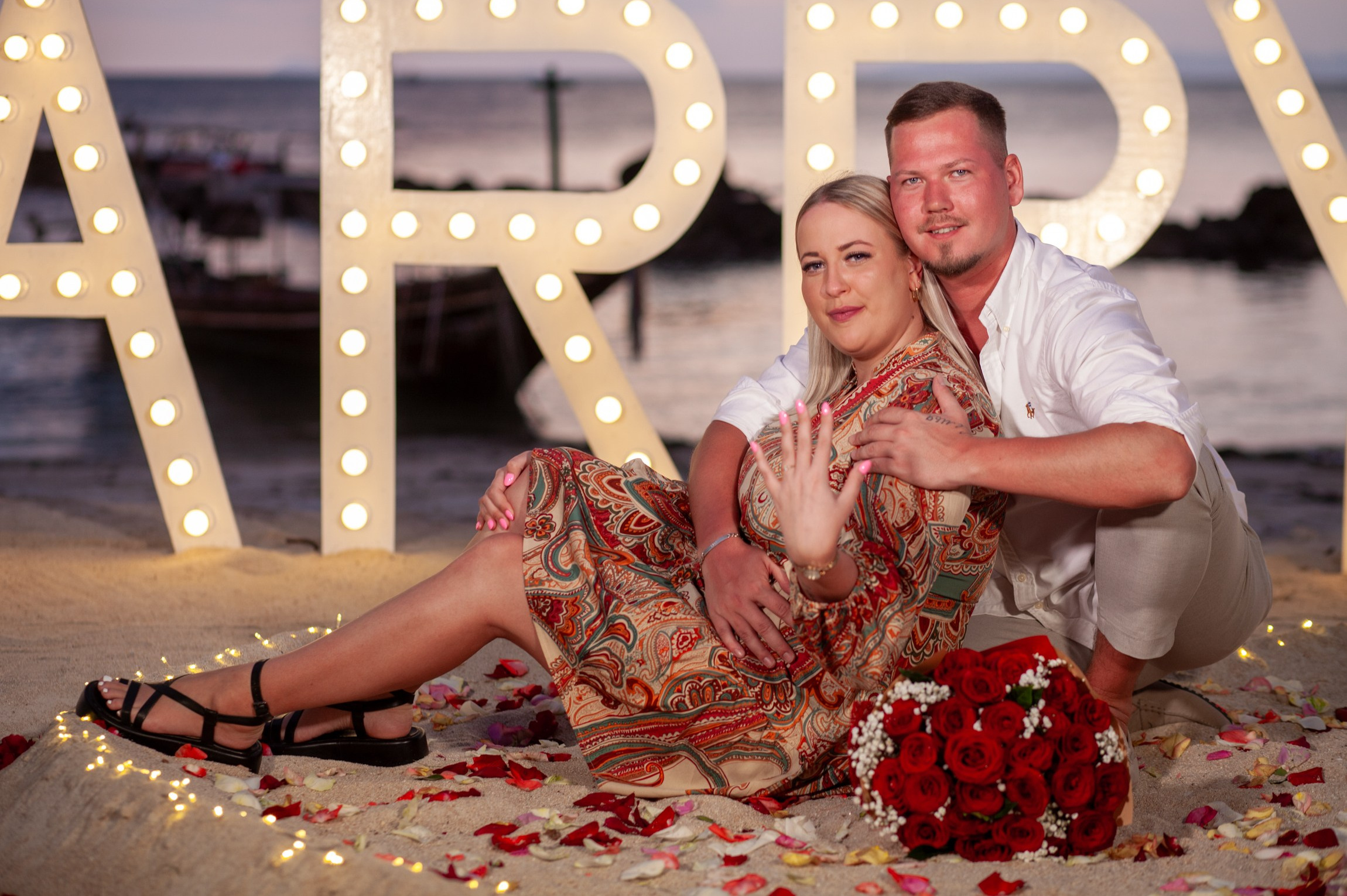 Romantic beach proposal setup in Koh Samui, Thailand with candles, flowers and ocean sunset view.
