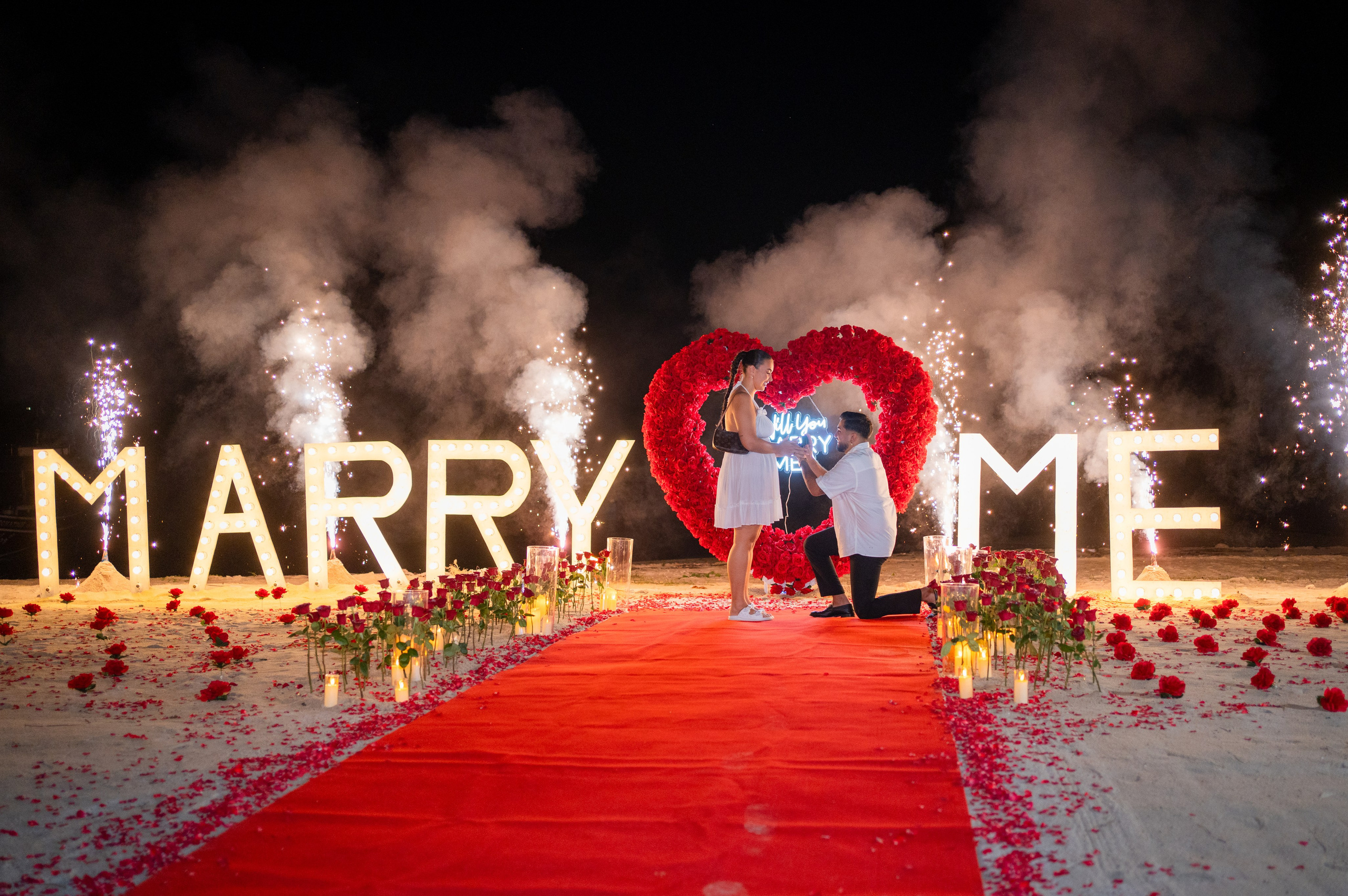Romantic beach proposal setup in Koh Samui, Thailand with candles, flowers and ocean sunset view.
