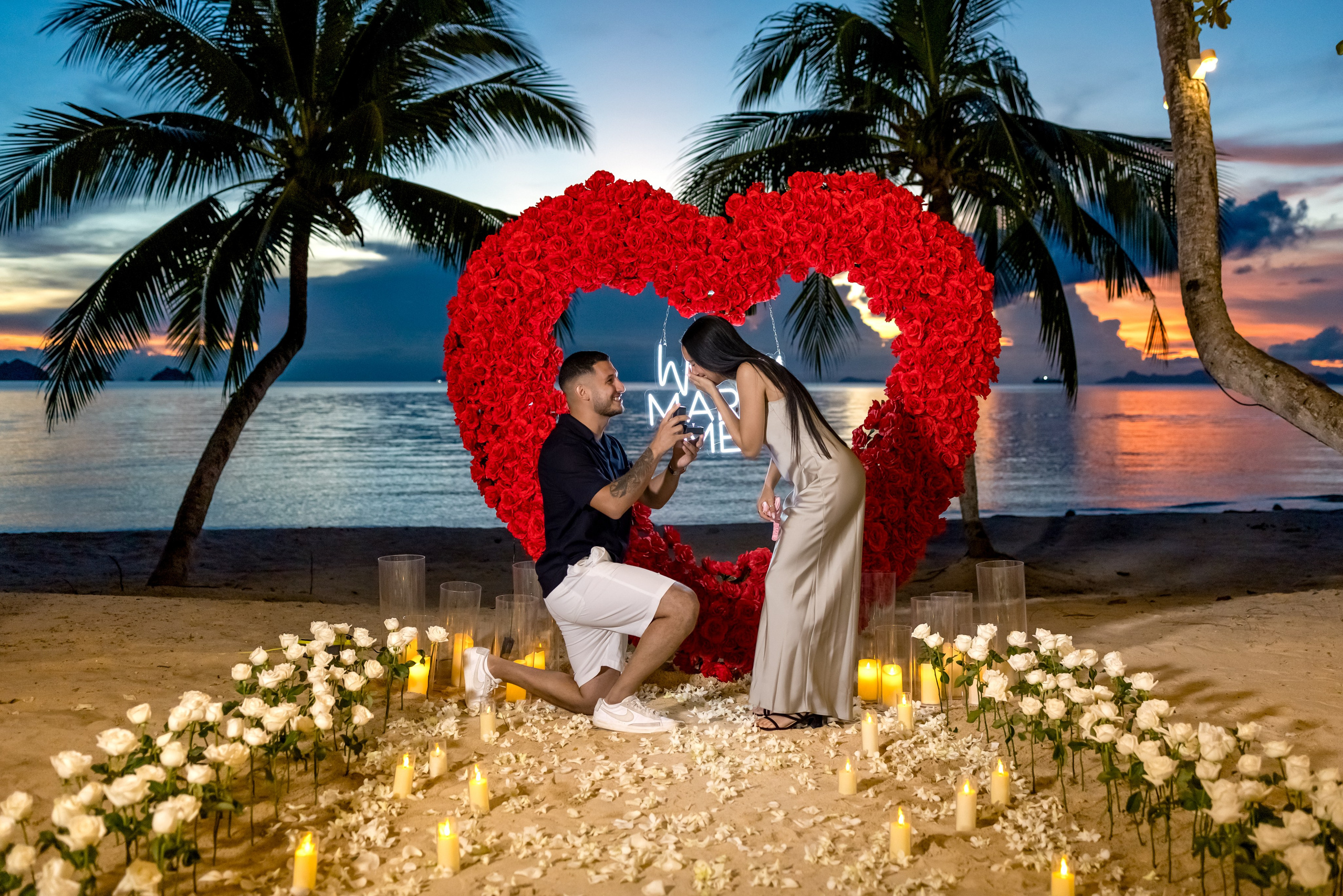 Elegant “Marry Me” beach proposal setup in Koh Samui with rose petals and tropical decor.