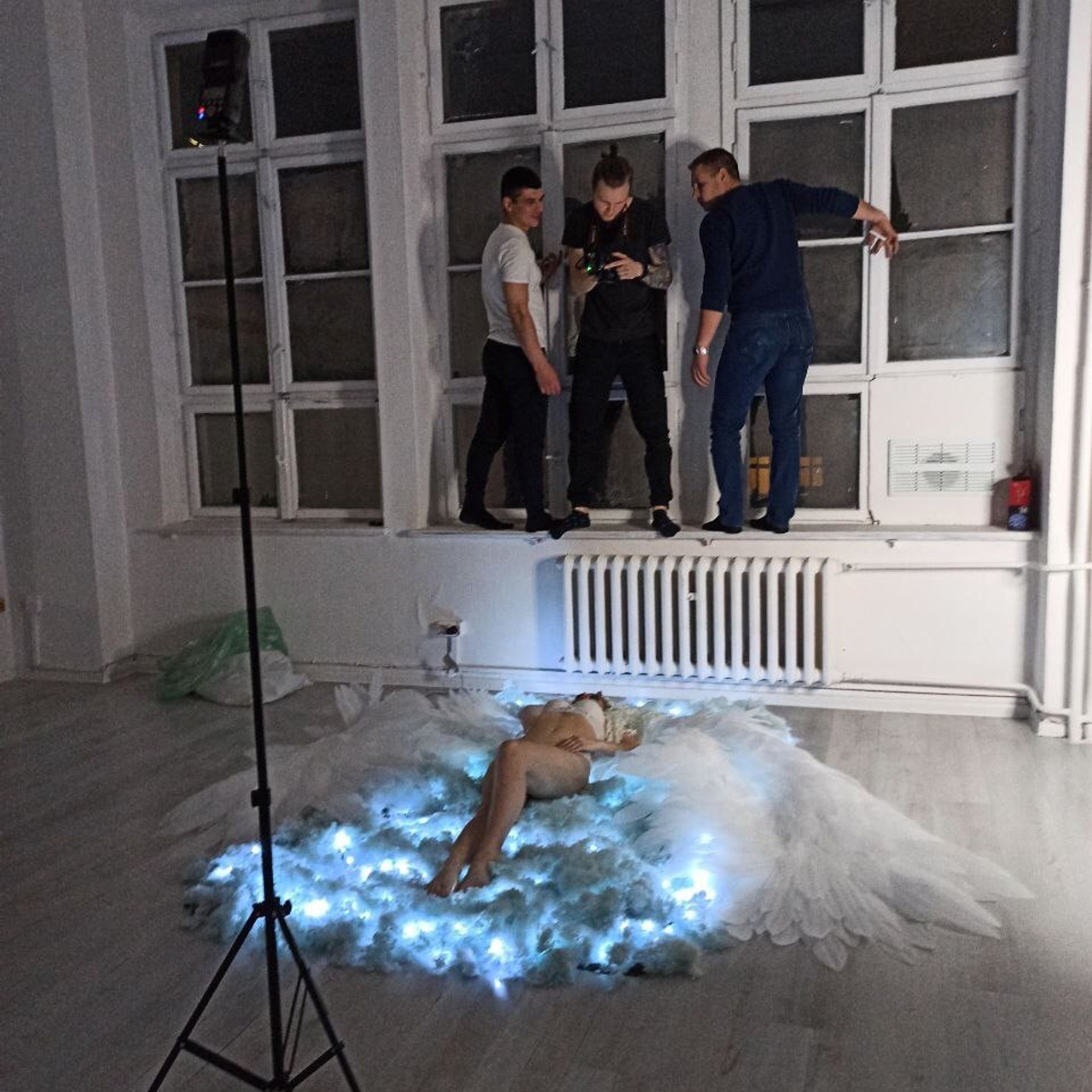 Behind the scenes creative photo production team reviewing shots during artistic portrait session with LED lighting