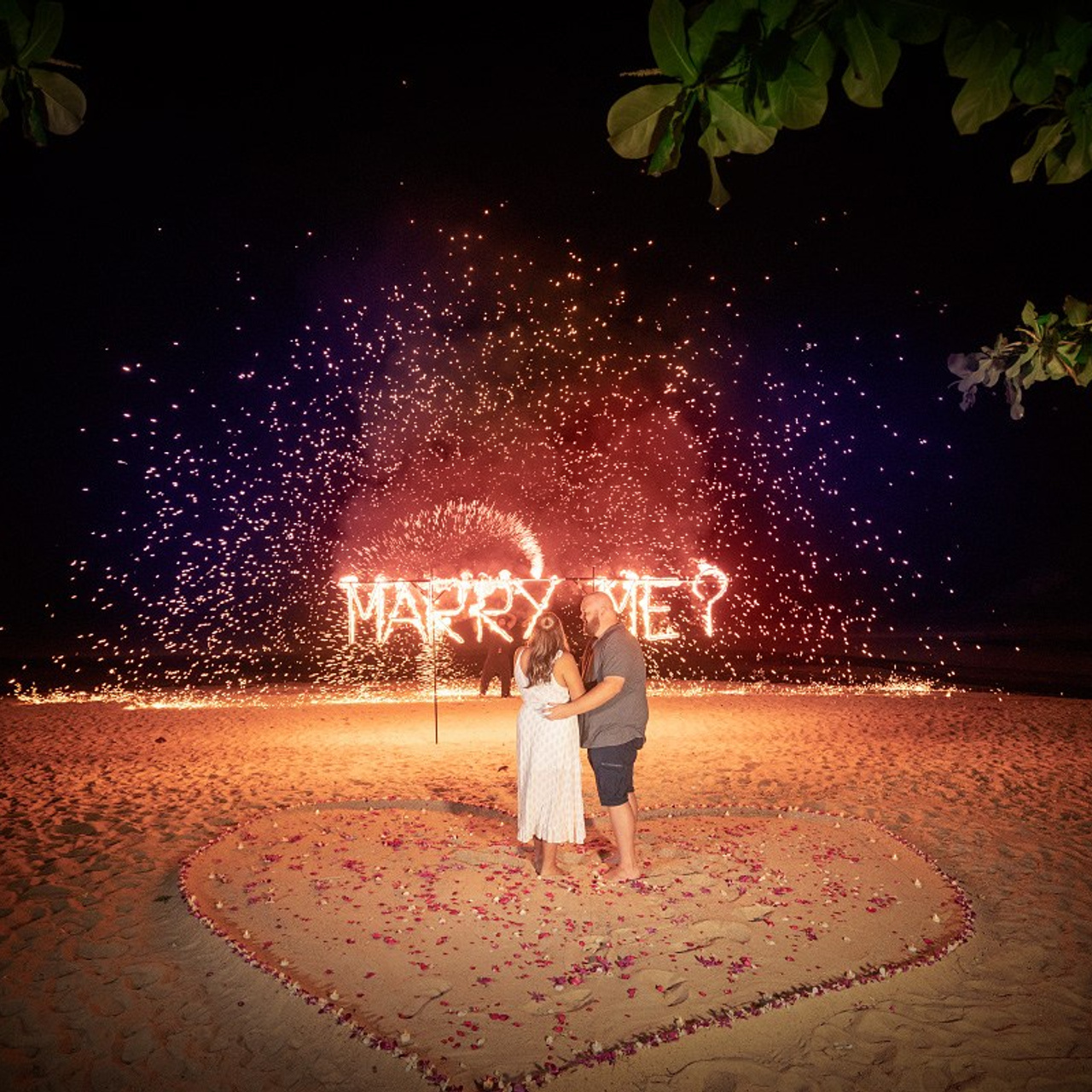 Romantic beach proposal setup in Koh Samui with candles and flower arch.