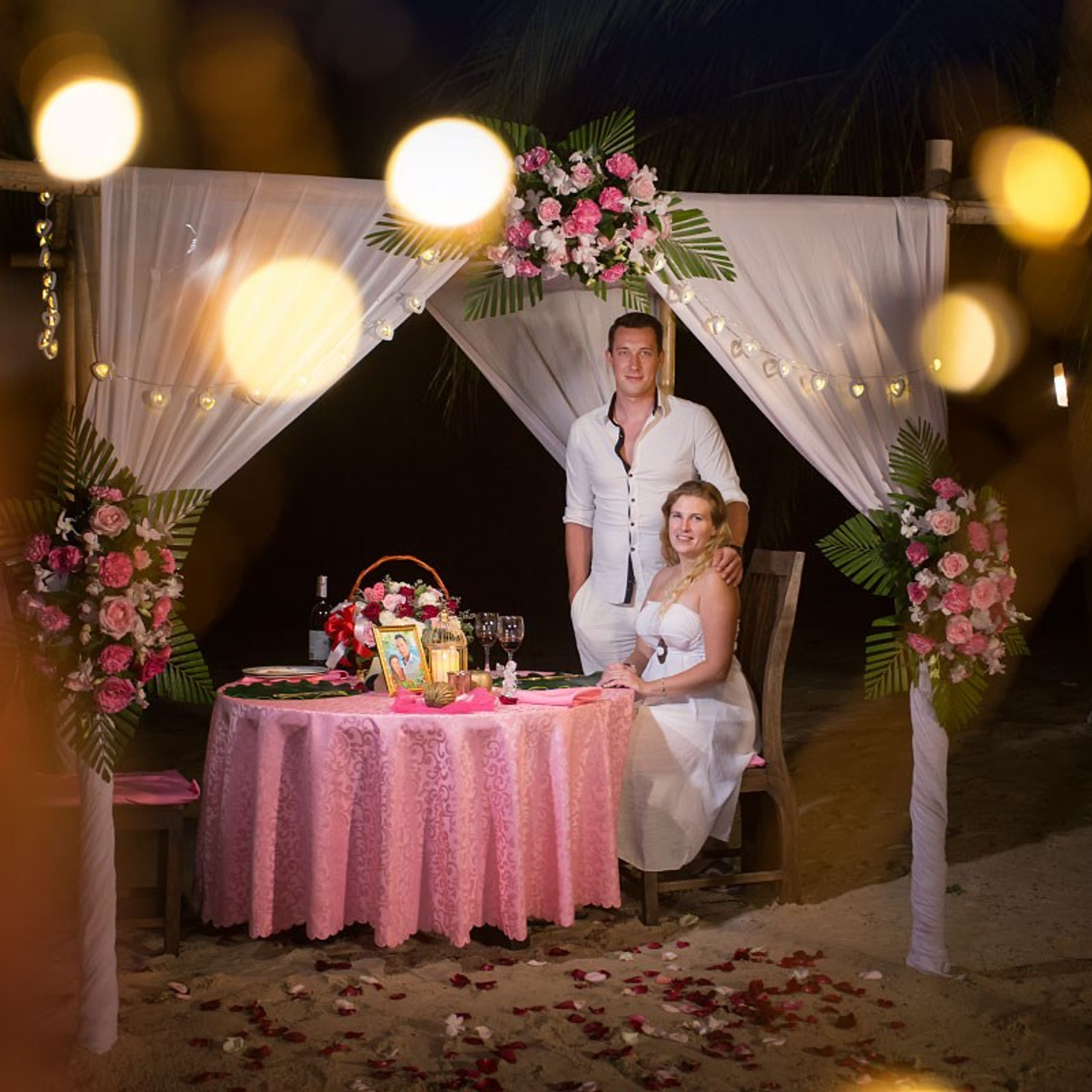 Romantic beach proposal setup in Koh Samui with candles and flower arch.