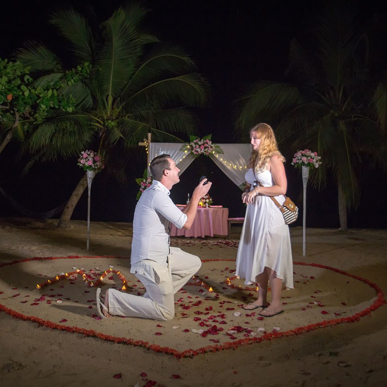 Romantic beach proposal setup in Koh Samui with candles and flower arch.