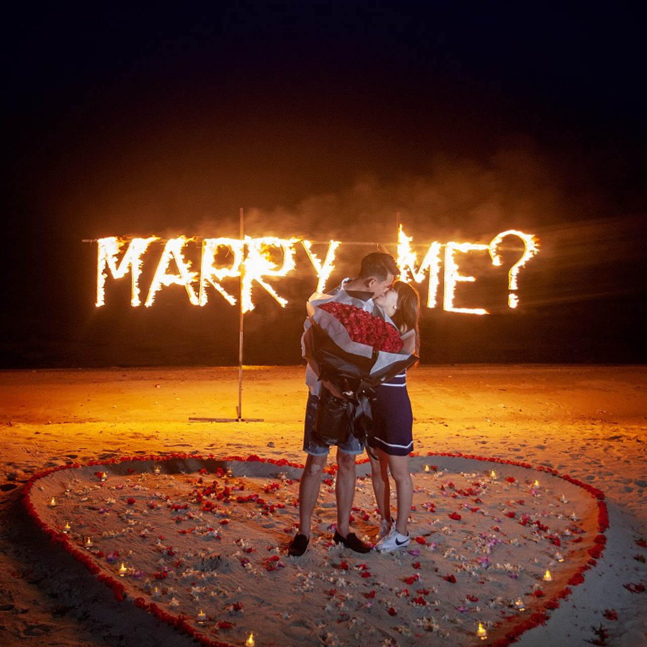 Romantic beach proposal setup in Koh Samui with candles and flower arch.