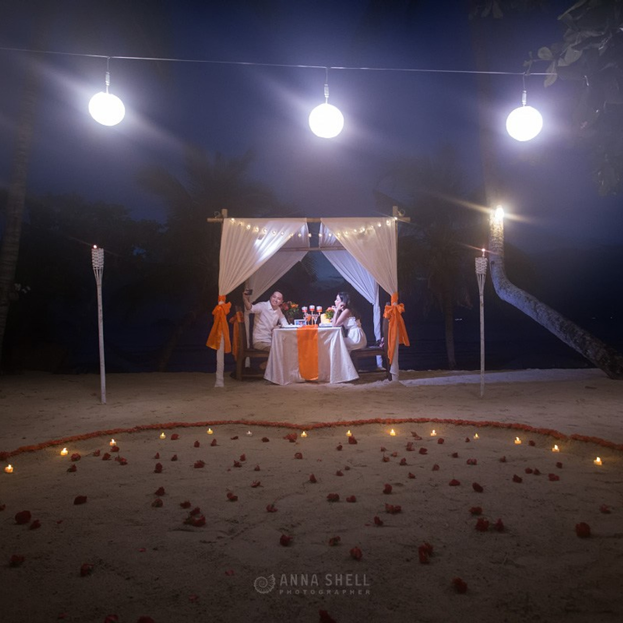 Romantic beach proposal setup in Koh Samui with candles and flower arch.