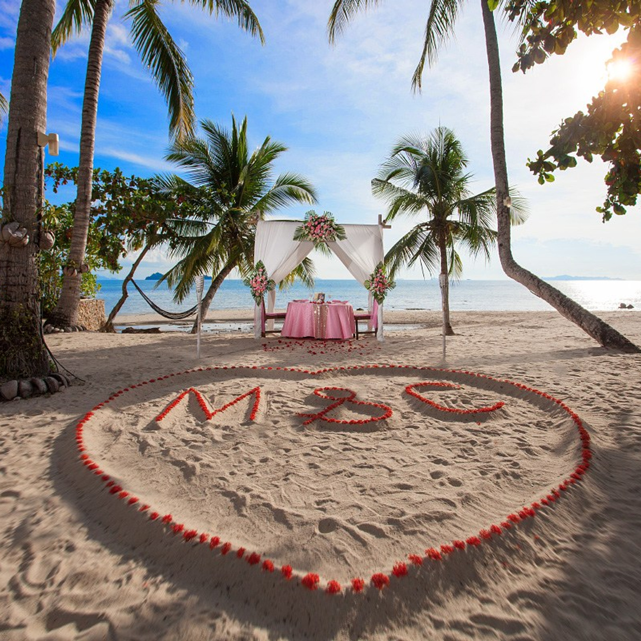 Romantic beach proposal setup in Koh Samui with candles and flower arch.