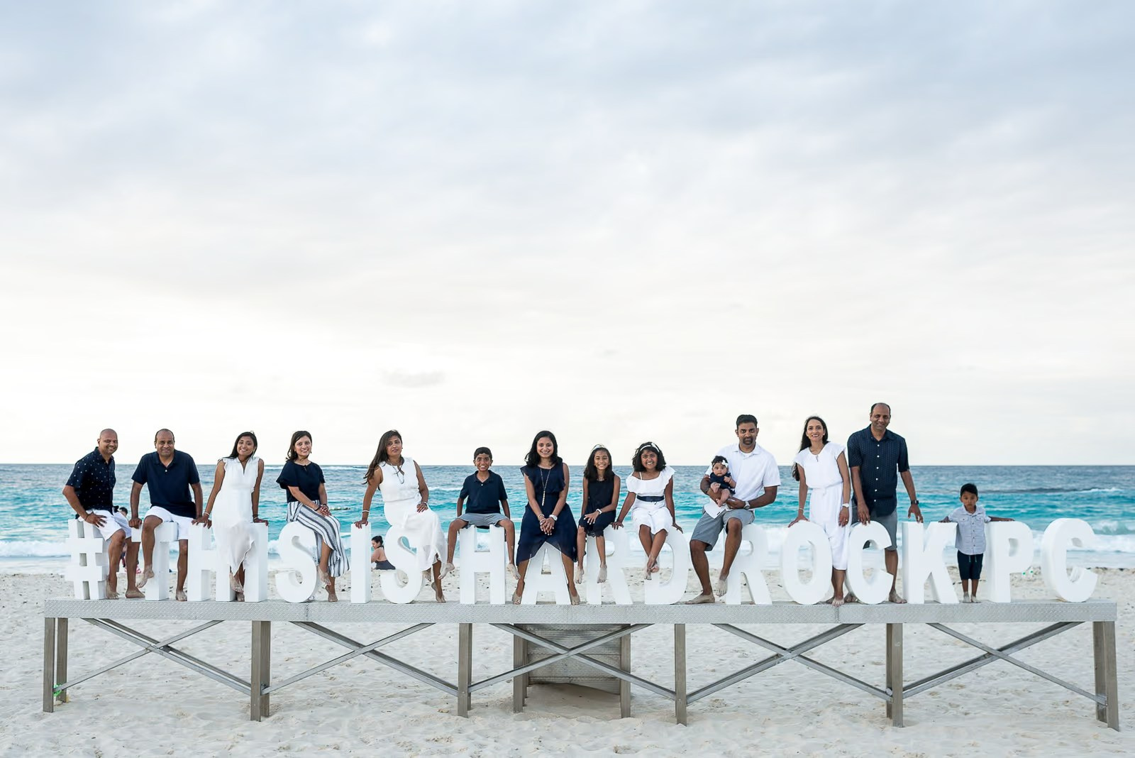 Familia sentada en las letras grandes de Hard Rock durante una sesión de fotos en la playa Bávaro