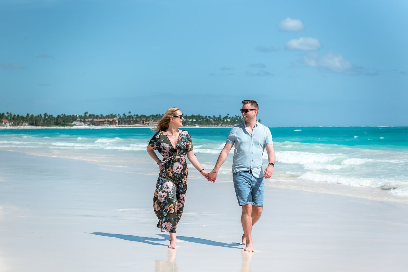 Smiling couple walking on white sand during a love story photoshoot on Bavaro Beach
