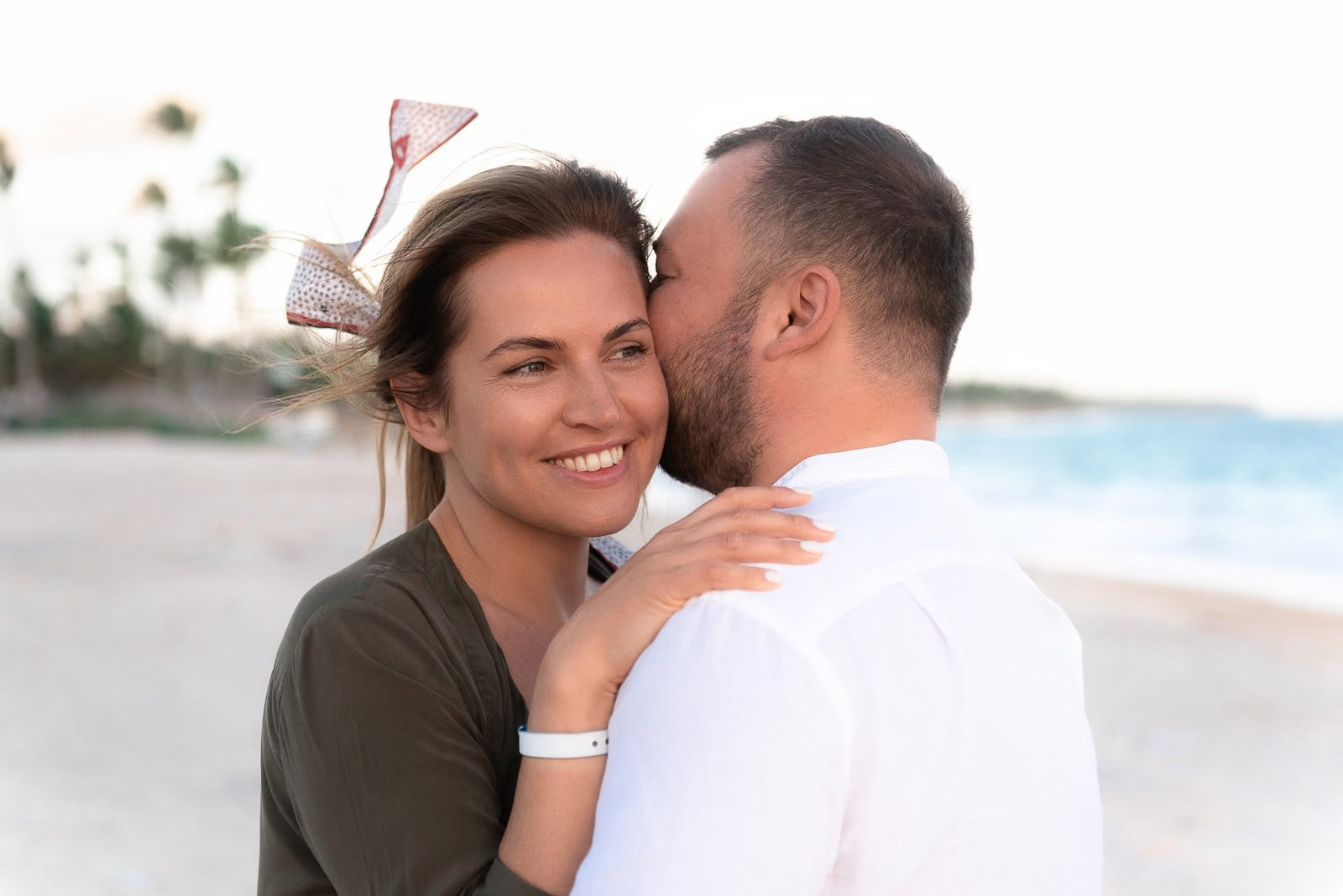 Woman smiling while her boyfriend kisses her on Bavaro Beach