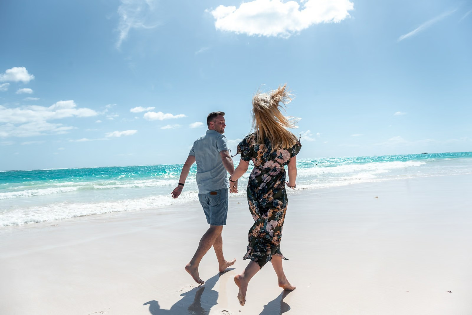 Happy couple running on white sand during a sunny photoshoot on Bavaro Beach