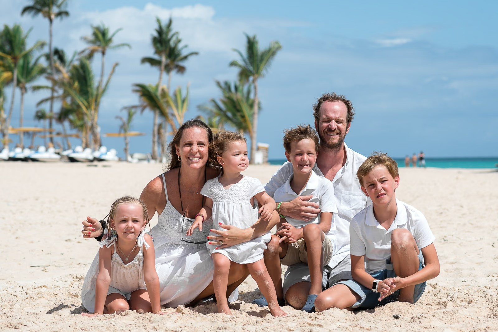 Family embracing by the Caribbean Sea during a Punta Cana beach photoshoot.