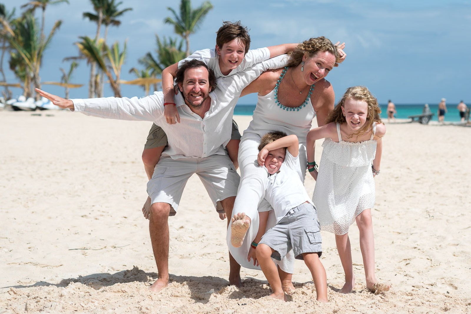 Parents walking barefoot with their children along Bavaro Beach during a family photoshoot in Punta Cana.