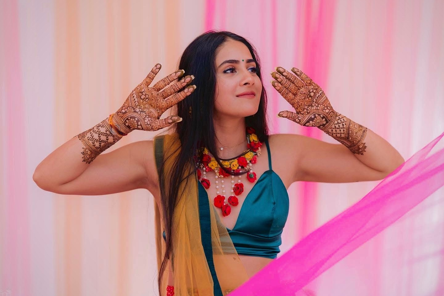 Bride dancing joyfully in yellow haldi outfit with colorful backdrop