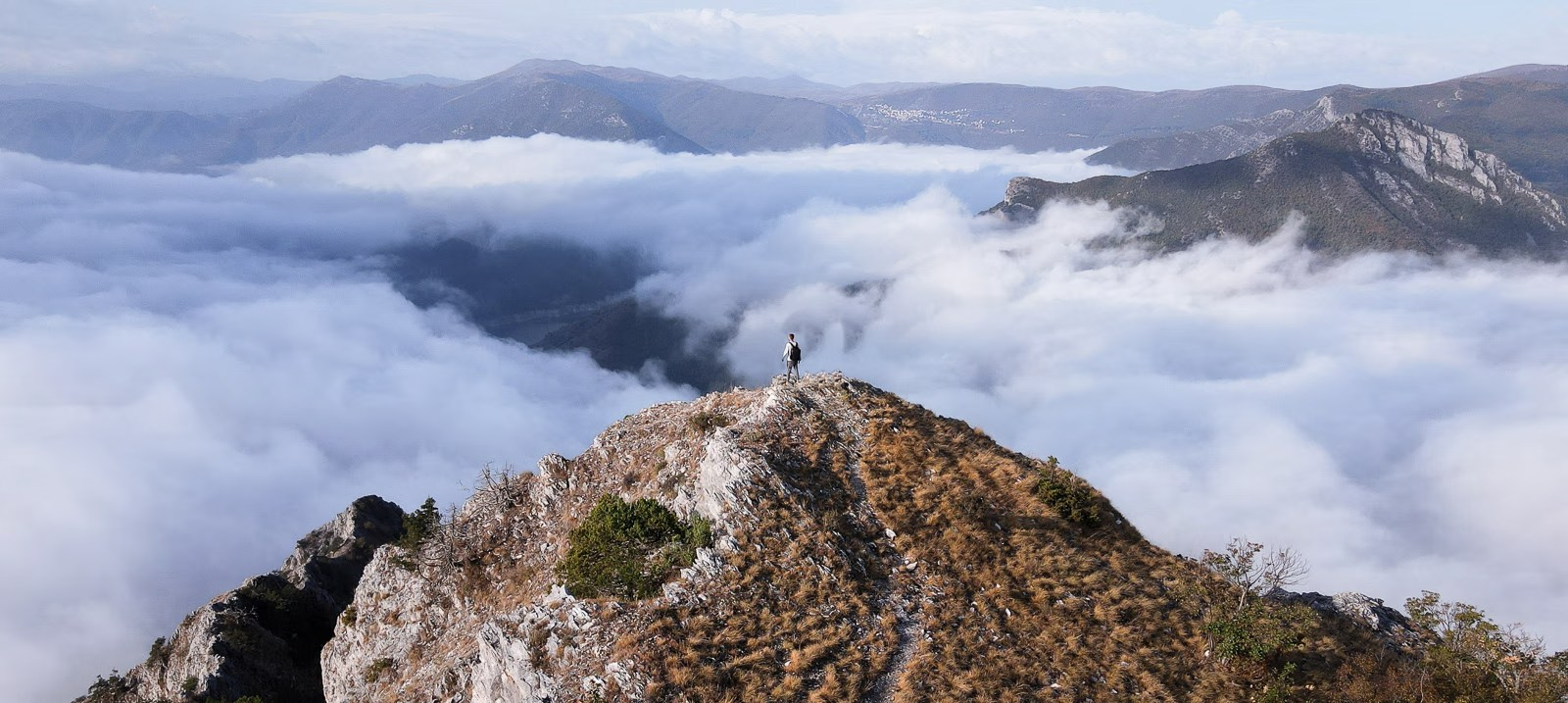 Photographer Alex Po stands on top of a mountain above the clouds