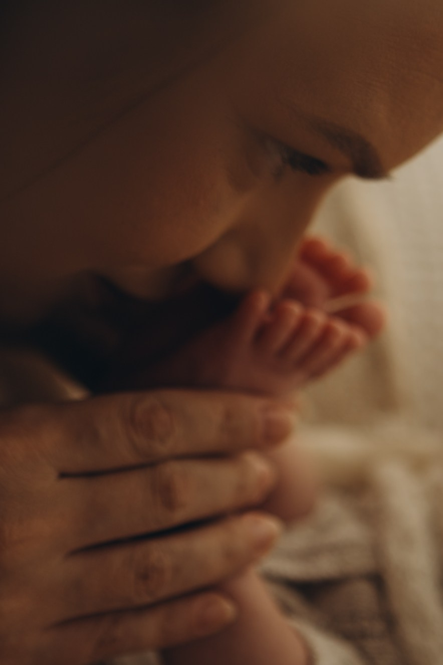 mãe faz carinho em pé de bebê em ensaio newborn com luz natural em Sorocaba