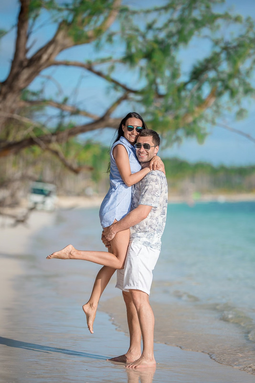 Husband lifting his wife as they smile during a beach photoshoot