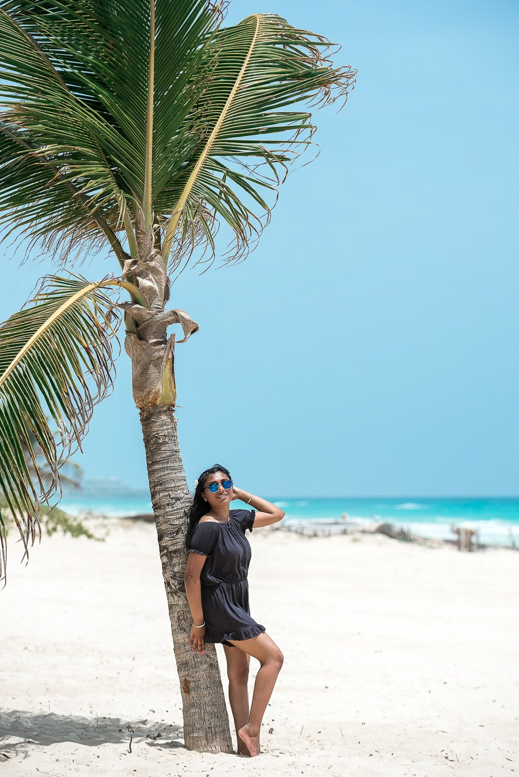 Indian woman leaning against a palm tree during a photoshoot in Punta Cana