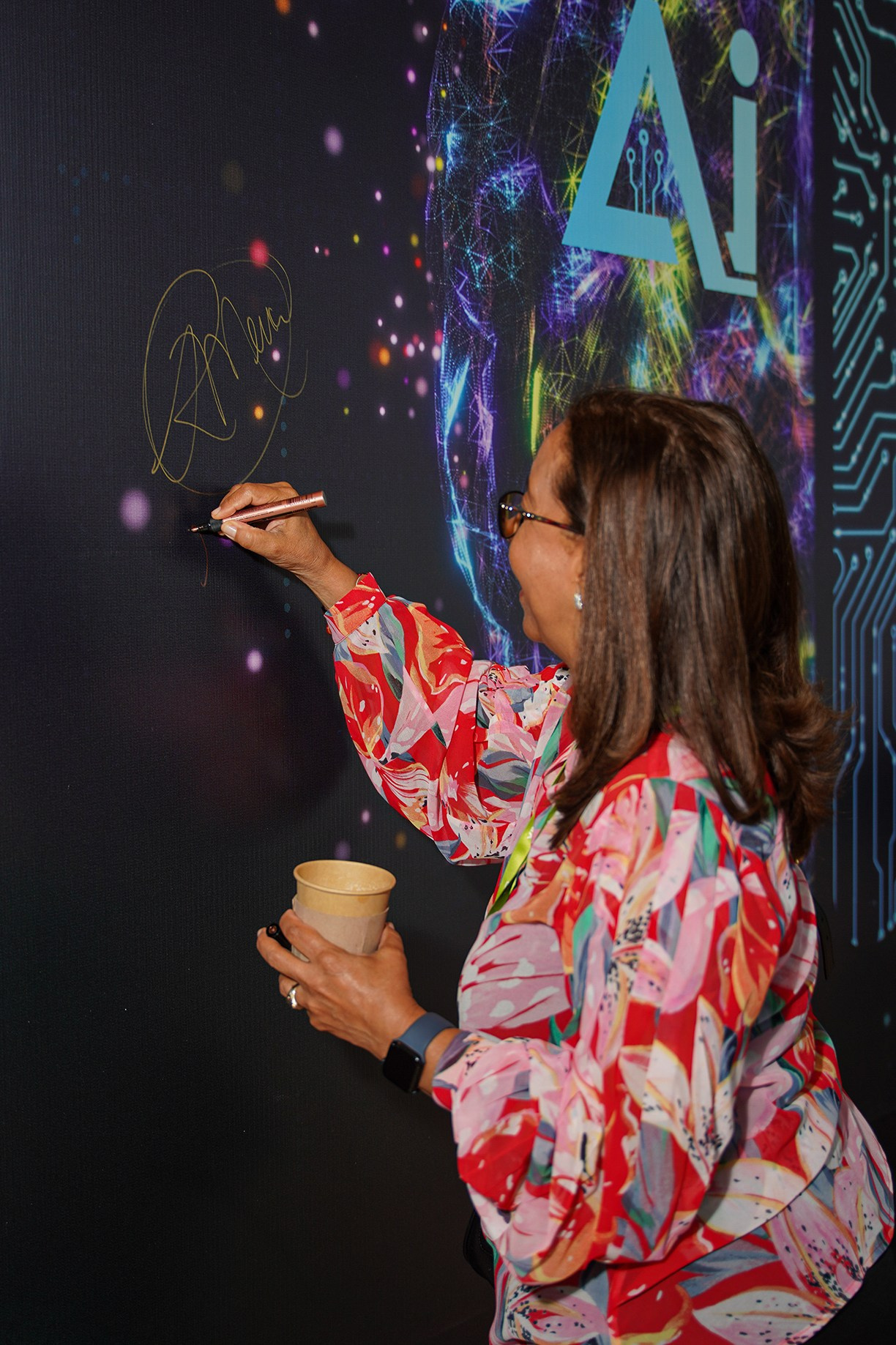 Attendee signing the branded event wall during corporate gathering.