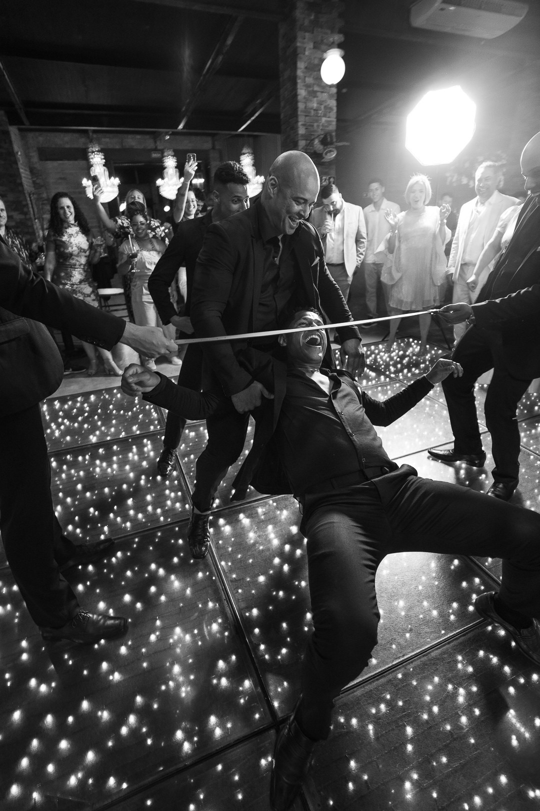 Fotografia espontânea da festa de casamento de Inga e Jack no Olaria Eventos em Betim MG com convidados celebrando intensamente e muita animação na pista.