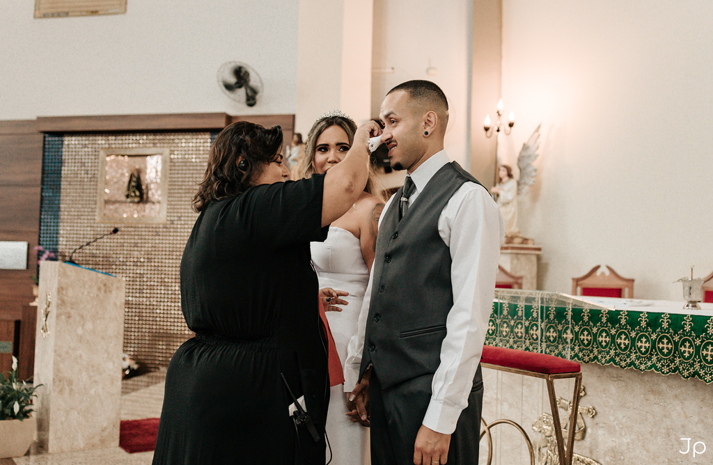 Casal posa para foto com celebrante no altar.