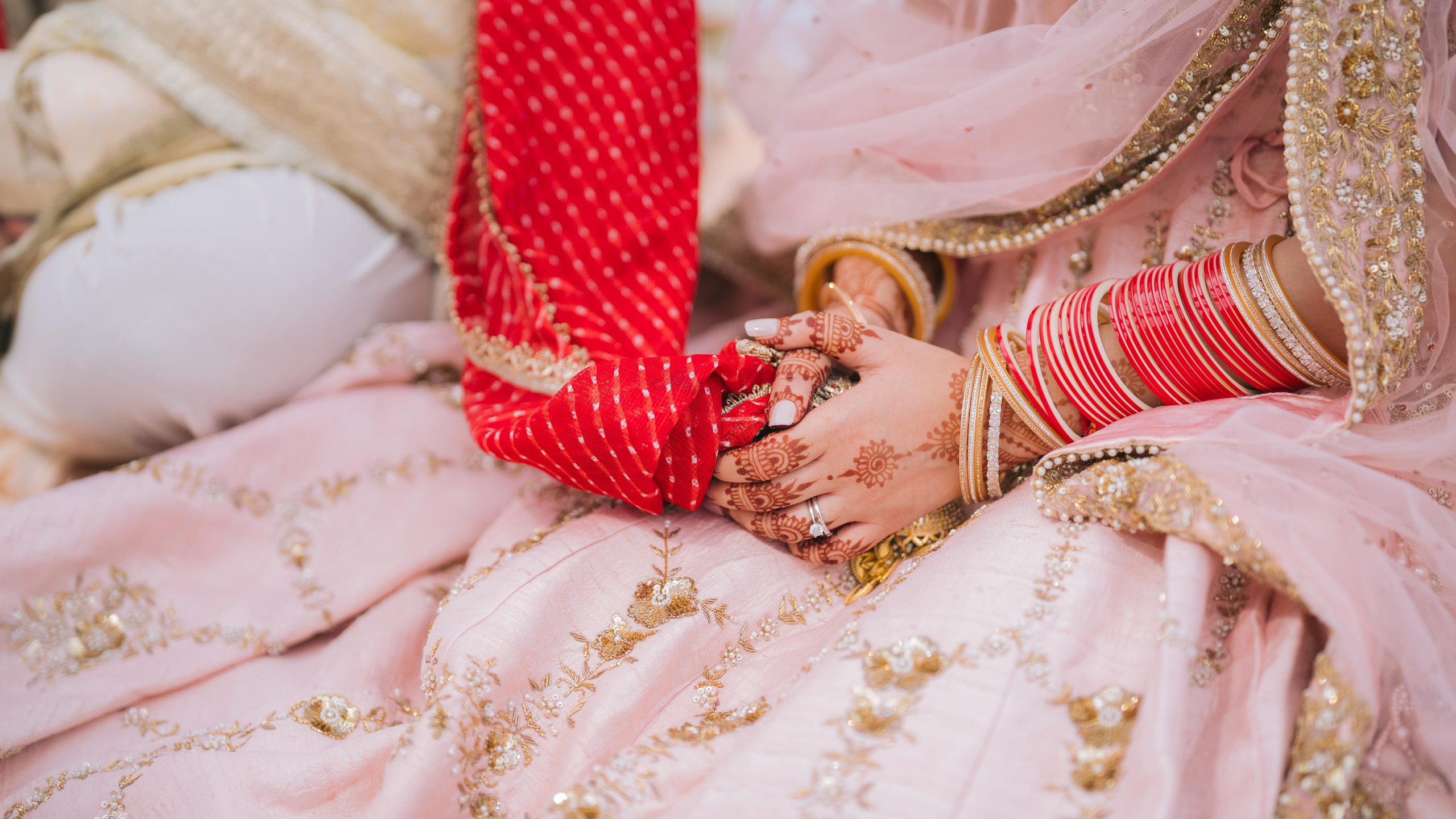 Bride adjusting bangles in pink bridal lehenga during wedding prep