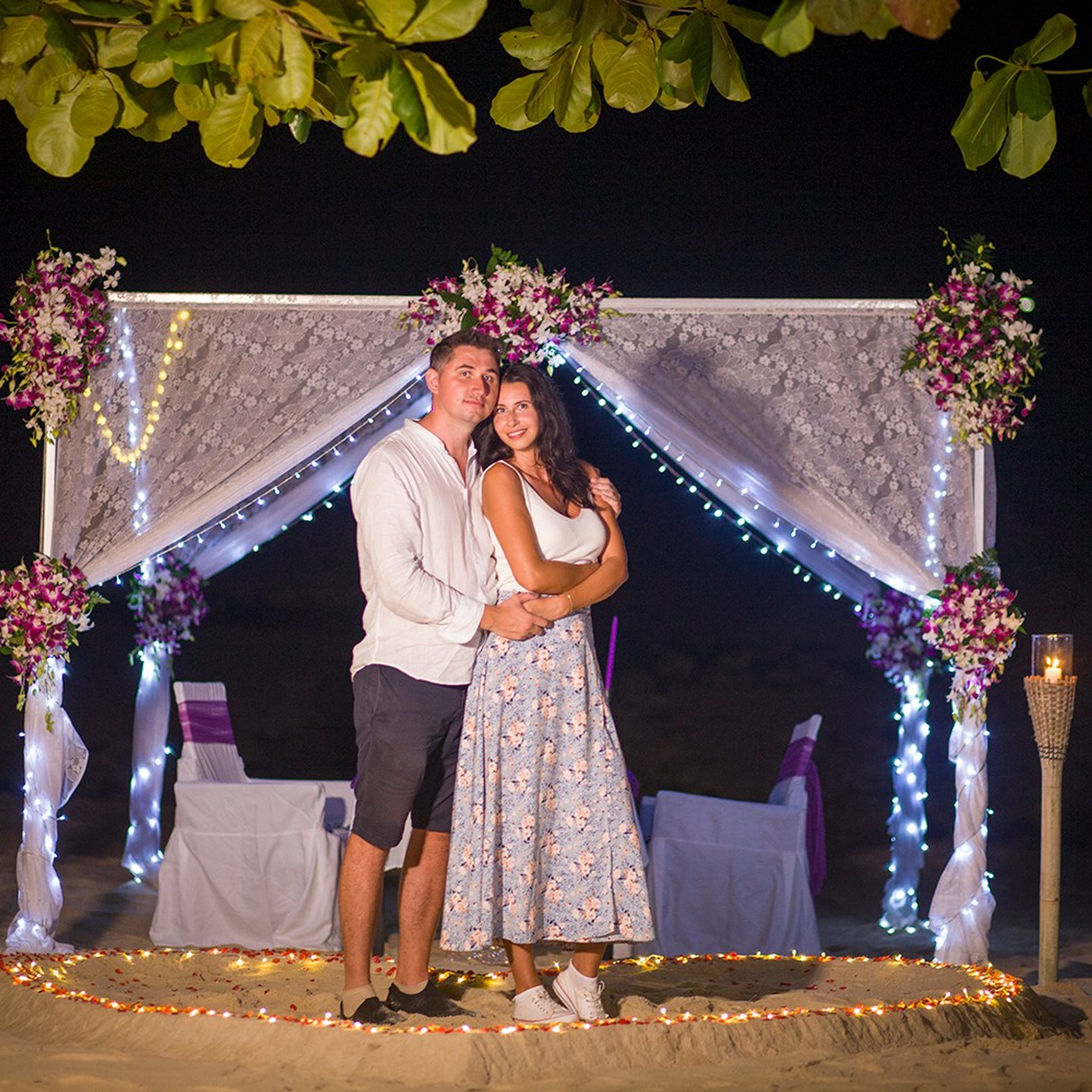 Romantic beach proposal setup in Koh Samui with candles and flower arch.
