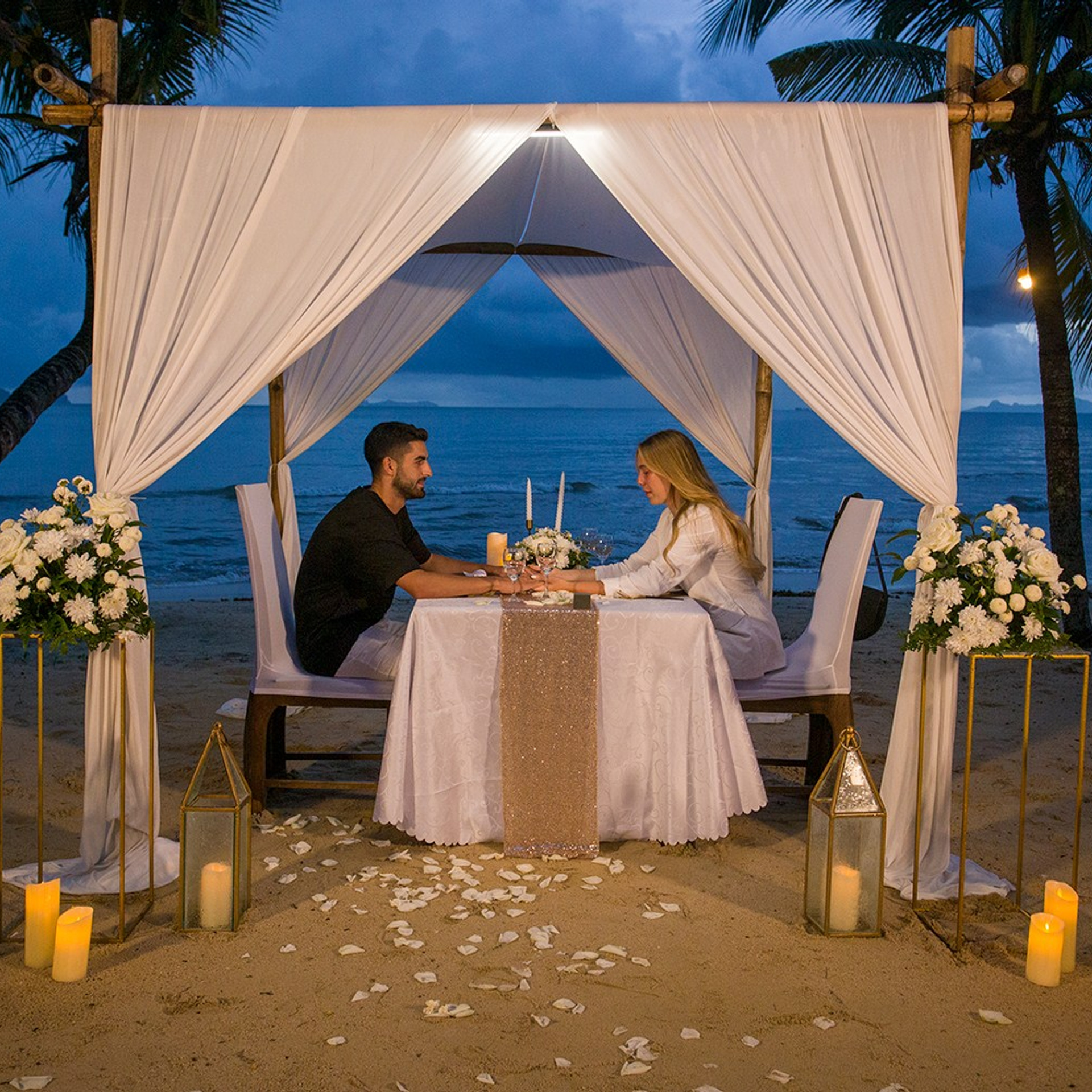 Romantic beach proposal setup in Koh Samui with candles and flower arch.