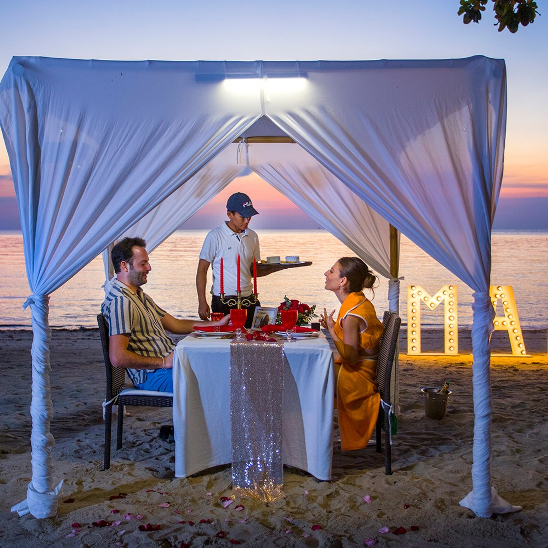 Romantic beach proposal setup in Koh Samui with candles and flower arch.