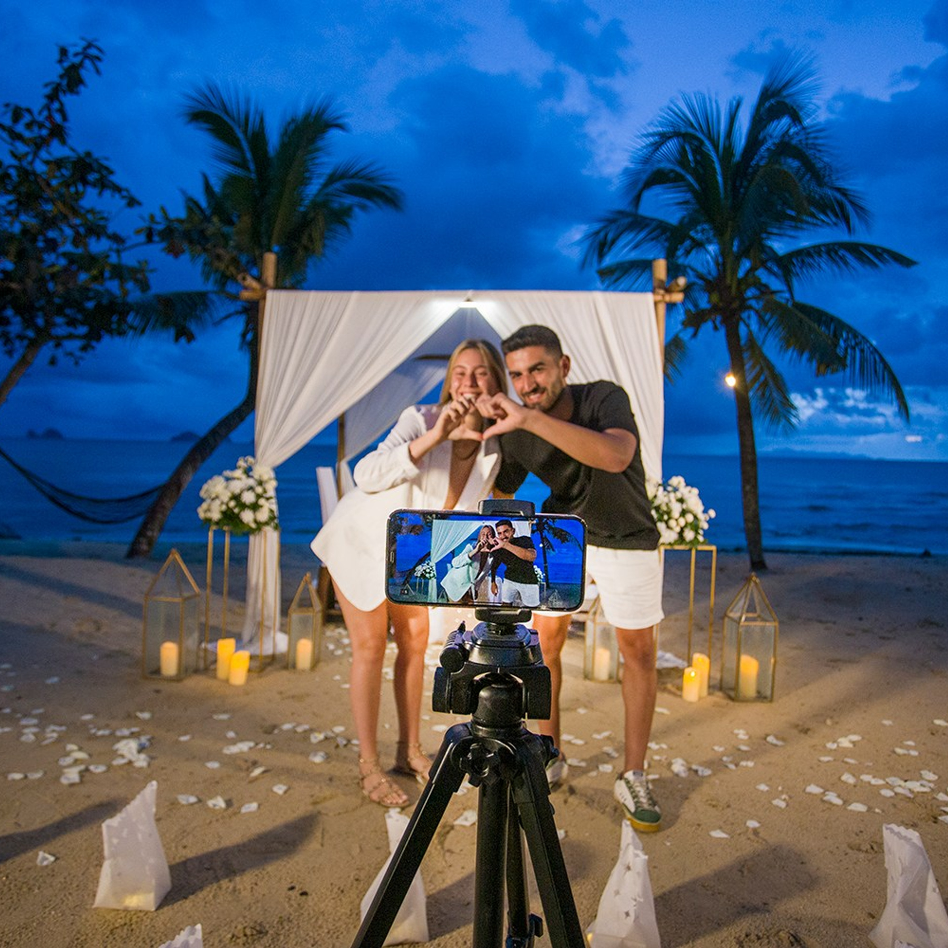 Romantic beach proposal setup in Koh Samui with candles and flower arch.