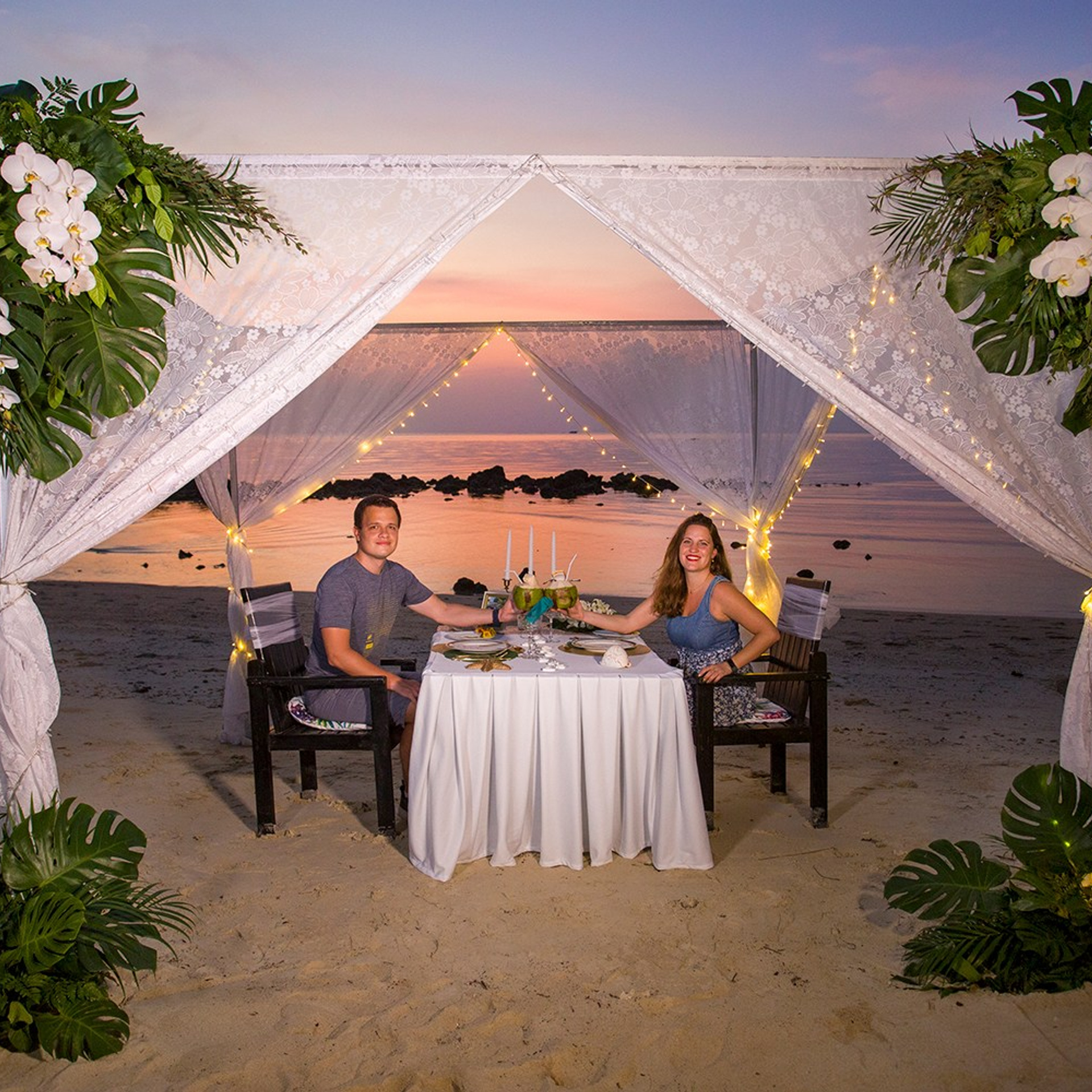 Romantic beach proposal setup in Koh Samui with candles and flower arch.