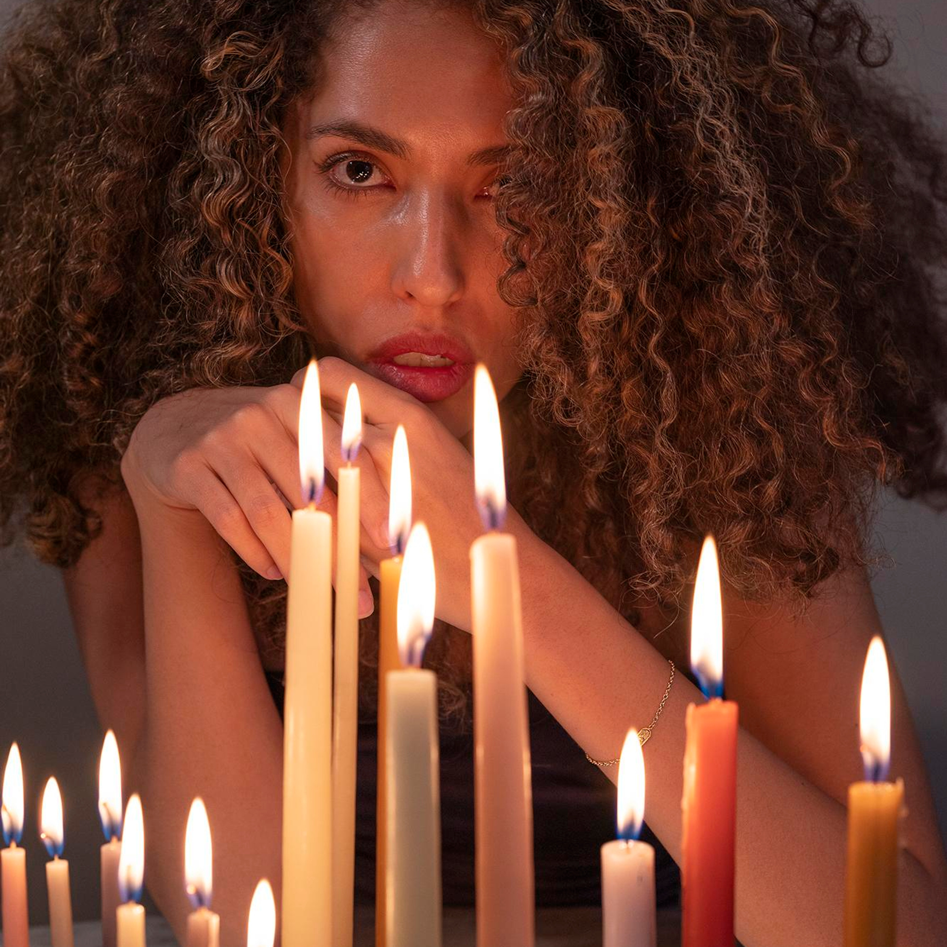 Artistic portrait of curly-haired woman surrounded by candles - portrait photographer Mexico City