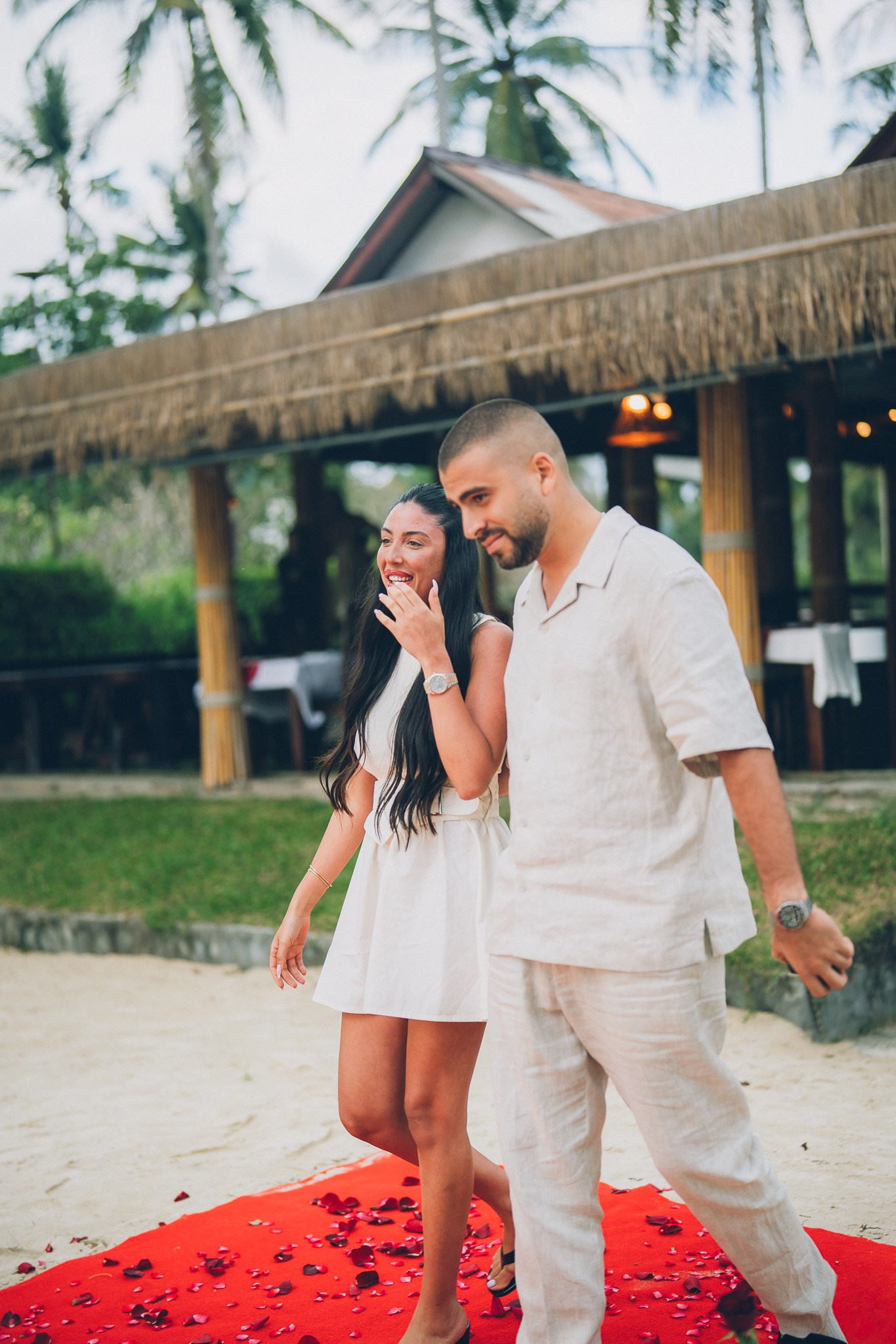 Happy engaged couple walking together on the beach in Pattaya after their romantic proposal.