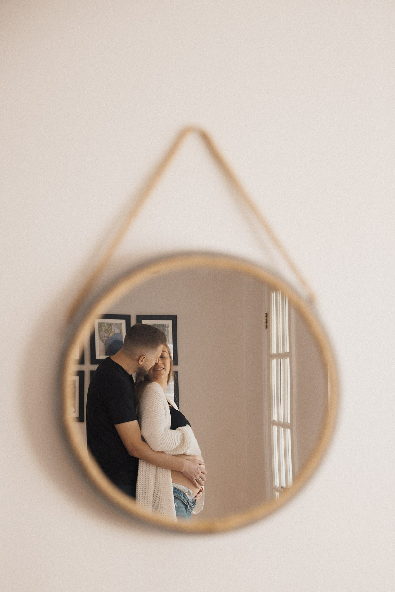 Expecting couple reflected in a small wall mirror at home