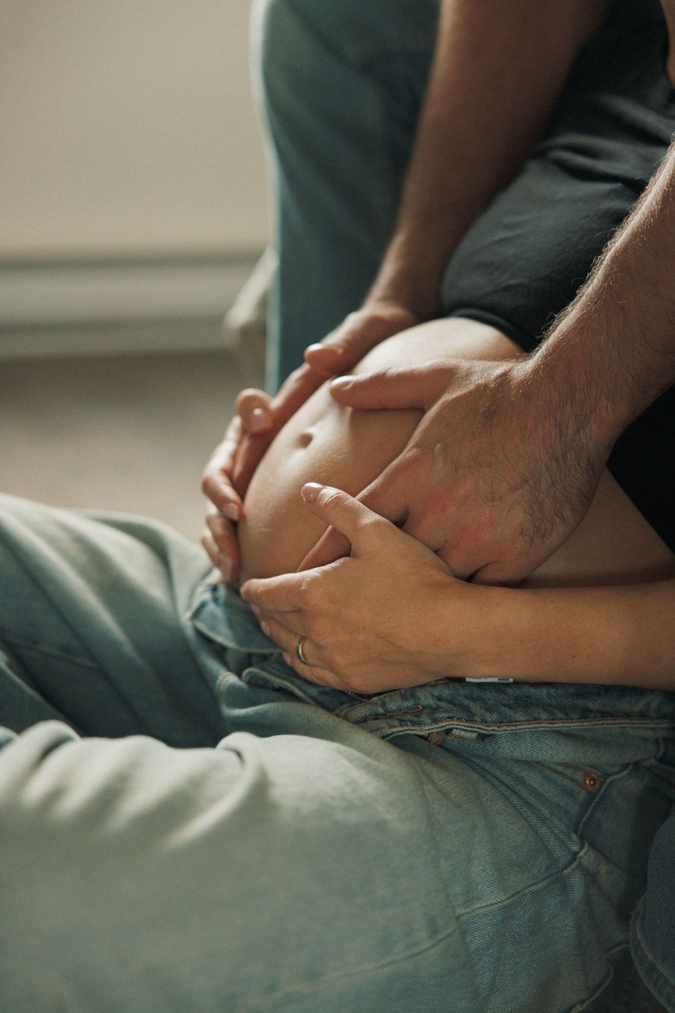 Parents’ hands resting gently on an expectant mother’s belly