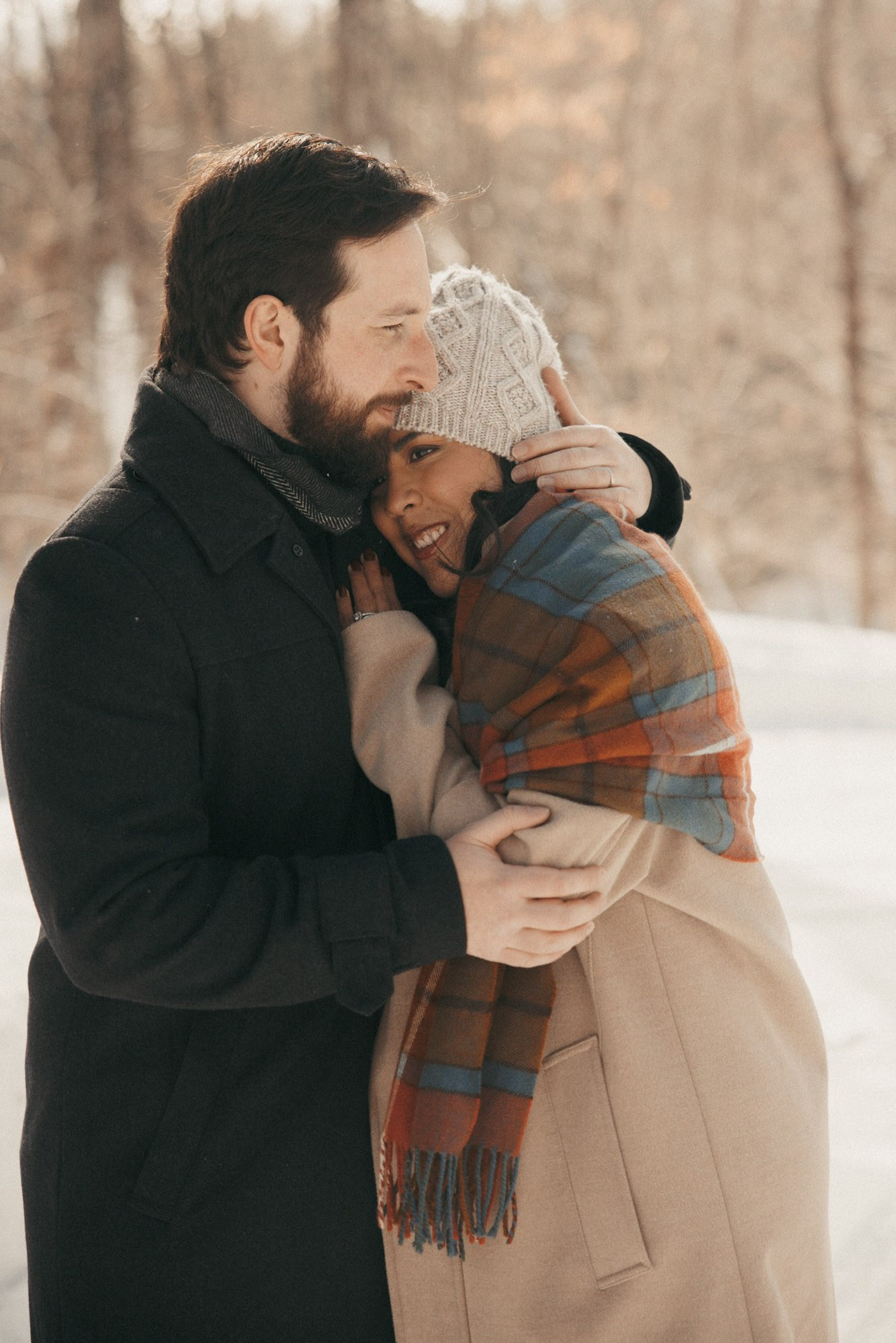 Expecting couple holding each other during a snowy winter session