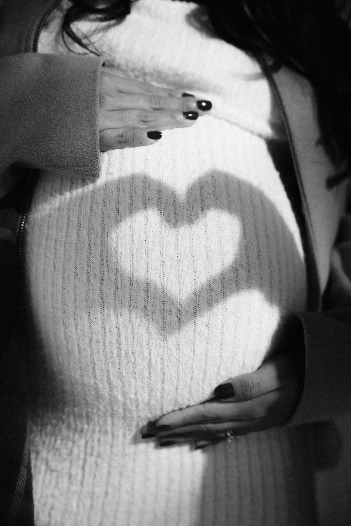 Heart-shaped shadow falling across an expectant mother’s belly