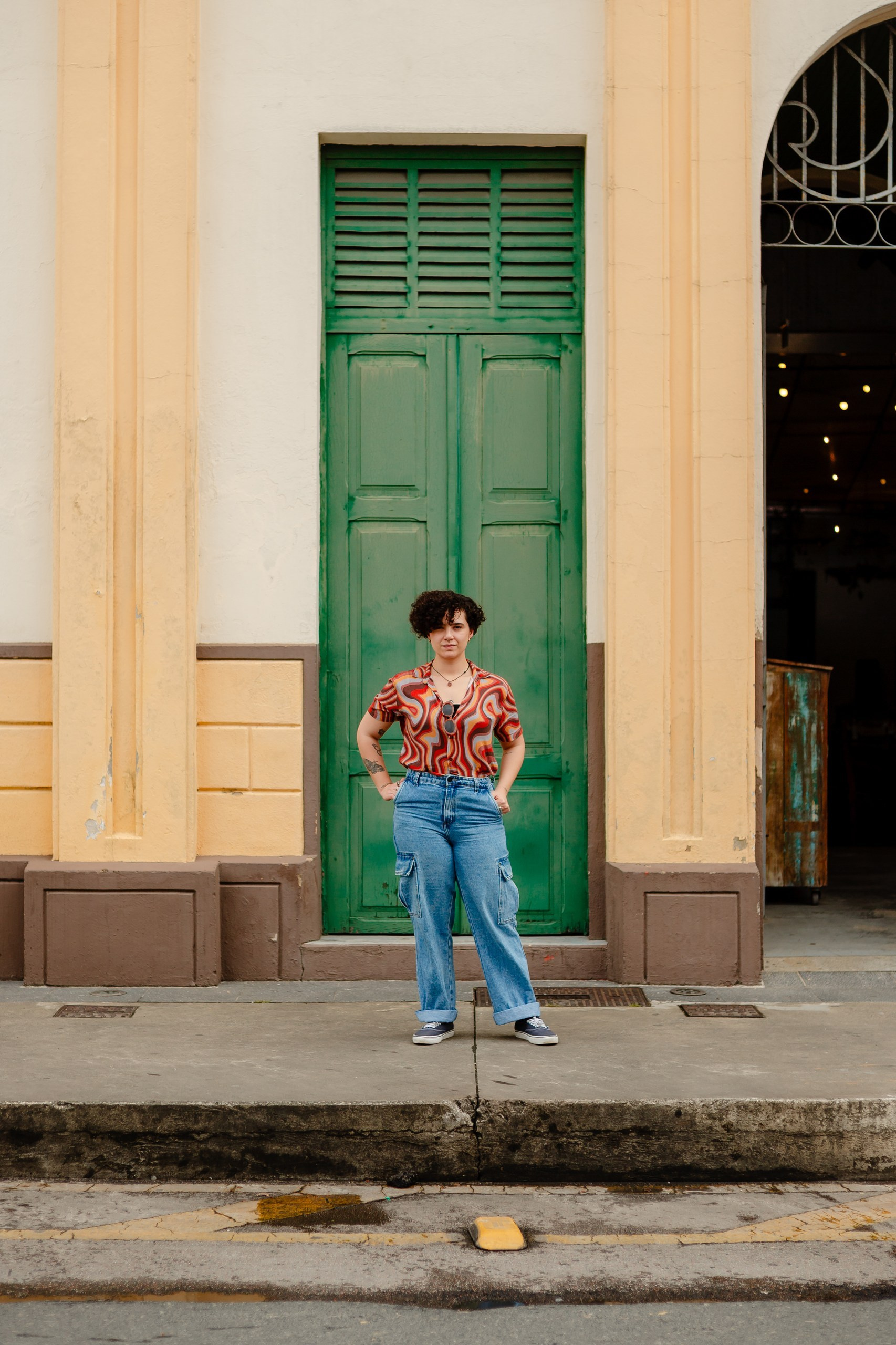 Mulher parada em frente a porta de prédio antigo.
